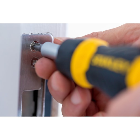 Close-up photo of Stanley 0-66-358 screwdriver being used to tighten a screw on a metal plate.