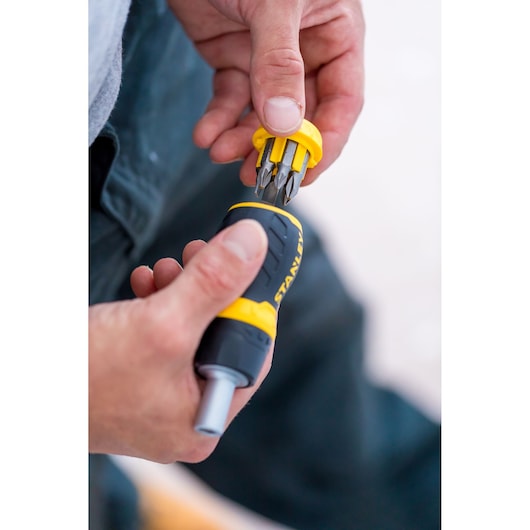Stanley 0-66-358 screwdriver with yellow bit holder and interchangeable bits, close-up handheld view.