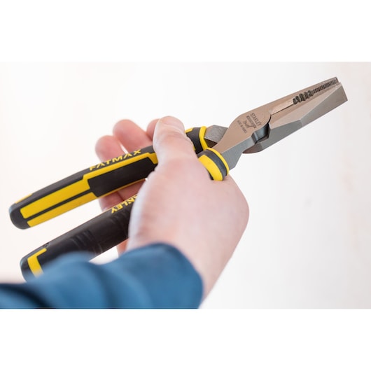 STANLEY 0-89-868 combination pliers with yellow and black handles, shown in hand during use.
