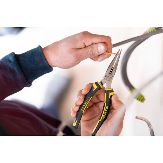 Photo of STANLEY 0-89-869 long nose pliers with black and yellow handle, held while gripping a wire, product in use.