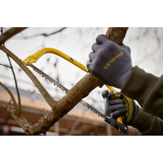 STANLEY 1-20-447 hand saw cutting a tree branch outdoors, close-up photography.
