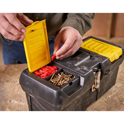 STANLEY 1-92-065 tool box with yellow latch and compartments storing screws and wall plugs, photo close-up.