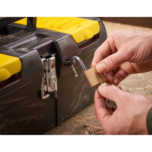 STANLEY 1-92-065 toolbox with yellow lid, close-up of hands locking with a padlock, product photography.