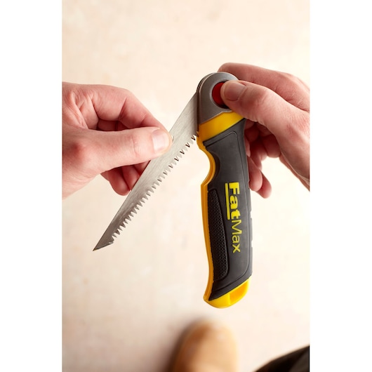 STANLEY FMHT0-20559 folding hand saw with black and yellow FatMax handle held in hand, angled close-up.