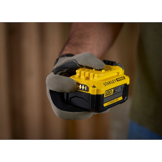 STANLEY SFMCB204 V20 4.0Ah lithium-ion battery held in a gloved hand, close-up.