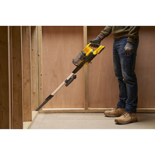 STANLEY SFMCVS001D1 handheld vacuum cleaner in use, yellow and black, cleaning a construction corner.