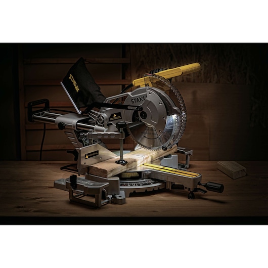 STANLEY SM18-B2C miter saw with sliding arm, angled blade, and dust bag on a wooden workbench.