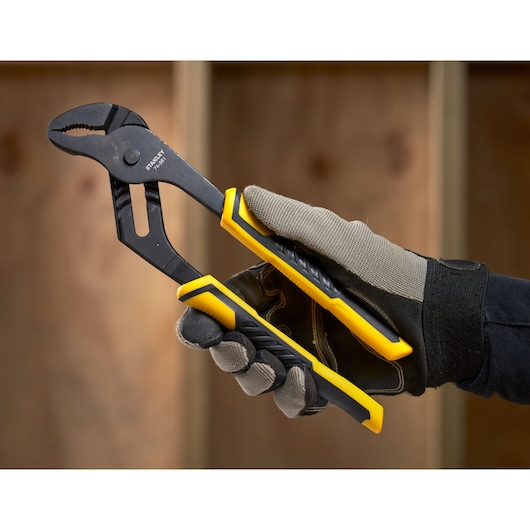 Photo of STANLEY STHT0-74361 adjustable pliers with yellow and black handles, held by a gloved hand.