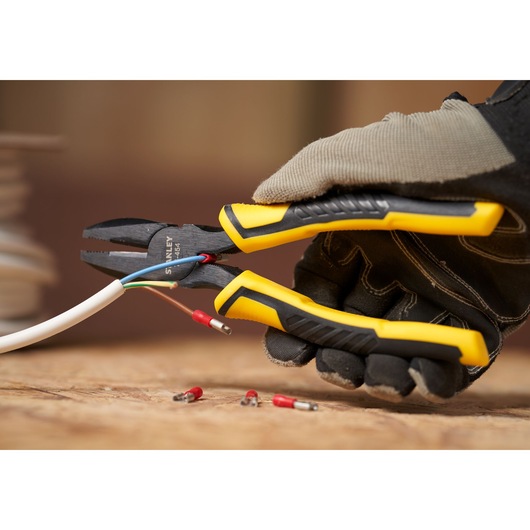 STANLEY STHT0-74367 pliers with yellow and black grip, cutting electrical wire, close-up view.