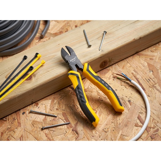 STANLEY STHT0-74455 diagonal cutting pliers with yellow and black grips on wooden board, surrounded by wires and nails.