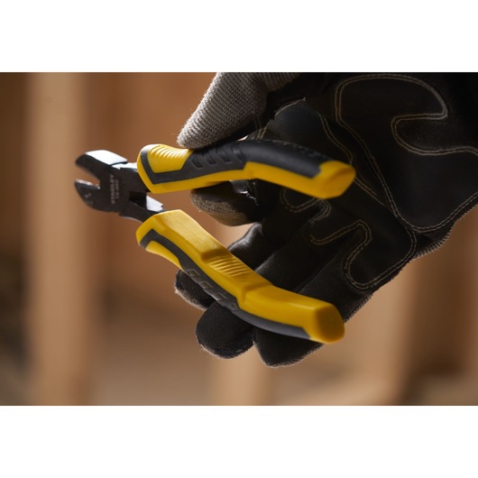 STANLEY STHT0-74455 yellow and black diagonal cutting pliers held by gloved hand, close-up photo.
