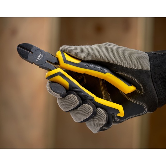 STANLEY STHT0-74455 diagonal cutting pliers with yellow and black handles held in gloved hand.