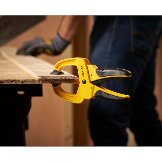 STANLEY STHT0-83199 photography of yellow and black clamp holding wood board, side angle.